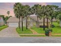 Charming home at sunset featuring palm trees, a brick driveway and walkway, and a well-maintained lawn at 526 Sabal Trail Cir, Longwood, FL 32779