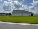 Side view of a single-story home featuring a well-kept lawn and simple architecture at 7172 Sw 135Th Pl, Ocala, FL 34473