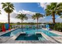 Inviting backyard oasis featuring a sparkling pool, serene lake view, playful games, and lush tropical landscaping at 884 Golden Bear Dr, Reunion, FL 34747