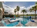 Stunning pool area with a jacuzzi, lounge chairs, a lake view, and palm trees, perfect for relaxation and outdoor enjoyment at 884 Golden Bear Dr, Reunion, FL 34747