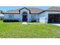 Charming one-story home featuring a gray roof, attached garage, and well-maintained front yard at 1930 Dolphin Drive, Kissimmee, FL 34759
