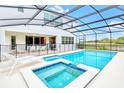 A luxurious screened-in pool and spa with an outdoor dining area and serene view at 2496 Rama Dr, Kissimmee, FL 34746