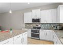 Bright kitchen with white cabinets, granite countertops, stainless steel appliances, and mosaic backsplash at 2704 Lobelia Dr, Lake Mary, FL 32746