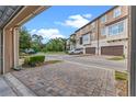 Townhome exterior showcasing attached garages, brick pavers, beautiful landscaping, and views of nearby green spaces at 2704 Lobelia Dr, Lake Mary, FL 32746