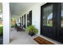 Inviting front porch with seating area and decorative plants, leading to a glass-paneled front door at 300 Royal Palm Ct, Longwood, FL 32779