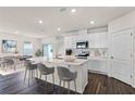 Bright kitchen with an island, white cabinets, barstool seating, stainless appliances, and dining area nearby at 5274 Scrub Mint Ln, Apopka, FL 32712