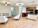 Open-concept living area with tile floors, seamlessly connecting to a kitchen with wooden cabinetry and modern appliances at 535 Aeolian Dr, New Smyrna Beach, FL 32168