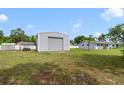 View of the large barn, lawn, white vinyl fence, and home with a blue sky on a sunny day at 5984 Ed Harris Ct, St Cloud, FL 34771