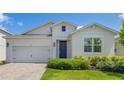 Inviting single-story home with a brick driveway, well-kept lawn, and a welcoming blue front door adorned with a wreath at 744 Curly Locks Loop, Apopka, FL 32703
