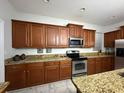 Well-appointed kitchen featuring granite countertops, stainless steel appliances, and beautiful wooden cabinets at 8894 Candy Palm Rd, Kissimmee, FL 34747