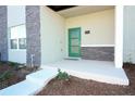 Inviting covered front porch with a bright green door and stylish stone accents at 976 Leader St, Davenport, FL 33896