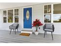Inviting front porch with a vibrant blue door, comfortable seating, and stylish decor at 1031 Morningside Dr, Eustis, FL 32726