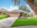 Beautiful house with a 2 car garage, lush green lawn, mature landscaping and front garden at 16631 Champions Ct, Clermont, FL 34711