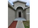 Inviting entryway with a dark wood door, arched alcove, and landscaped flower bed at 304 Lake Daisy Loop, Winter Haven, FL 33884