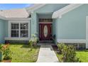 Inviting entryway showcases a decorative red door with glass accents, complemented by colorful landscaping and stone details at 36646 Oconee Ave, Eustis, FL 32736
