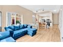 Open-concept living space with a comfy blue sectional, dining area, and modern kitchen featuring white cabinets at 4600 Yellowgold W Rd # 102, Kissimmee, FL 34746