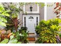 Inviting front entryway with a white door, lush landscaping, and a welcoming 'Bless this Home' doormat at 7642 Park Hill Ave, Leesburg, FL 34748