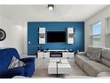 Comfortable living room featuring a modern entertainment center and stylish blue accent wall at 884 Laurel View Way, Groveland, FL 34736