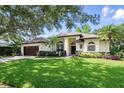 Beautifully landscaped single-story home featuring a lush green lawn and elegant architectural details at 9491 Wickham Way, Orlando, FL 32836