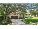 Attractive single-story home with a two-car garage, brick-lined driveway, and mature trees at 9491 Wickham Way, Orlando, FL 32836