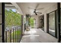 View of the covered tiled balcony featuring black railing and ceiling fan overlooking green landscaping at 1055 Kensington Park Dr # 203, Altamonte Springs, FL 32714