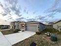 Single-story house with a two-car garage, a concrete driveway, and green front lawn at 1147 Pomelo St, Davenport, FL 33837