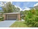 Brick home with an attached garage and mature landscaping, including manicured bushes and palm trees at 200 Hummingbird Ln, Longwood, FL 32779