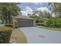 View of the two-car garage with neutral paint, driveway, and manicured landscaping in the surrounding yard at 200 Hummingbird Ln, Longwood, FL 32779