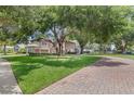 Beautiful home exterior with large trees and a brick driveway at 25537 High Hampton Cir, Sorrento, FL 32776