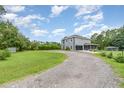 View of the side of a grey home featuring an expansive lawn, gravel driveway, and screened in porch at 32125 Wekiva Pines Blvd, Sorrento, FL 32776