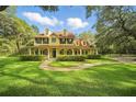 Inviting yellow two-story home featuring a charming wrap-around porch and mature landscaping at 4200 Joslyn Ln, Lady Lake, FL 32159