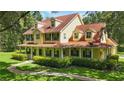 Stunning yellow two-story home featuring a charming wrap-around porch and verdant landscaping at 4200 Joslyn Ln, Lady Lake, FL 32159