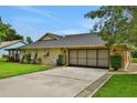 View of attached two-car garage and well-kept lawn, with lush green bushes at 5929 Hatteras Dr, Port Orange, FL 32127