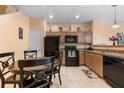 Cozy kitchen with tile floors, wood cabinets, and black appliances adjacent to dining area at 7625 Long Island Dr, Kissimmee, FL 34747