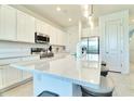 Modern kitchen featuring white cabinets, stainless appliances, island with seating and stone countertops at 832 Longboat Dr, Davenport, FL 33896