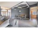 Open-concept living and dining area featuring modern gray walls, coffered ceiling, and sleek wood floors at 1662 Canoe Creek Rd, Oviedo, FL 32766