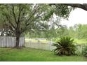 Serene backyard view with lush greenery, mature trees, and a picturesque fence lining the waterfront at 1868 Hammock Moss Dr, Orlando, FL 32820