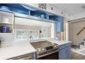 Stylish kitchen with countertop cooktop, blue cabinets, and pass-through window to the dining area at 244 N Leavitt Ave, Orange City, FL 32763