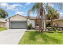 Charming single Gathering home featuring an attached garage, palm tree and landscaped yard at 3280 Pinto Dr, Kissimmee, FL 34746