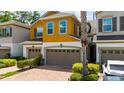 Two-story townhouse featuring an attached garage and tropical landscaping at 3508 Brighton Park Cir, Belle Isle, FL 32812