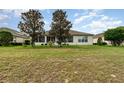 Expansive backyard featuring lawn, trees, screened lanai, and exterior of the single-story home at 8865 Se 119Th St, Summerfield, FL 34491
