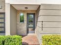 Close-up of the townhome entrance featuring a modern door, brick walkway, and landscaped bushes at 9533 Mere Pkwy, Orlando, FL 32832