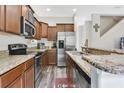Well-equipped kitchen featuring stainless steel appliances, granite countertops, wooden cabinetry, and modern flooring at 10656 Savannah Plantation Ct, Orlando, FL 32832