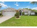 Charming single-story home featuring a well-manicured lawn, a two car garage, and decorative garden at 176 Hidden View Dr, Groveland, FL 34736
