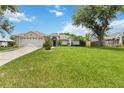 Charming single-story home featuring a lush green lawn, two car garage, and mature landscaping at 176 Hidden View Dr, Groveland, FL 34736