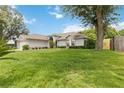 Well-maintained single-story home with a lush green lawn, mature trees, and manicured landscaping at 176 Hidden View Dr, Groveland, FL 34736