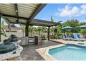 Backyard oasis with a covered outdoor kitchen, bar, and luxurious pool with sun loungers at 3618 Rothbury Dr, Belle Isle, FL 32812
