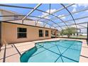 Backyard view of an in-ground swimming pool with screen enclosure and blue skies at 5200 Sunset Canyon Dr, Kissimmee, FL 34758