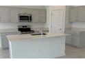 A modern kitchen featuring stainless steel appliances, an island, and ample cabinet space at 680 Sand Pine Ln, Haines City, FL 33844