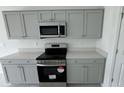 Close-up view of the kitchen with stainless steel appliances and light gray cabinets at 680 Sand Pine Ln, Haines City, FL 33844